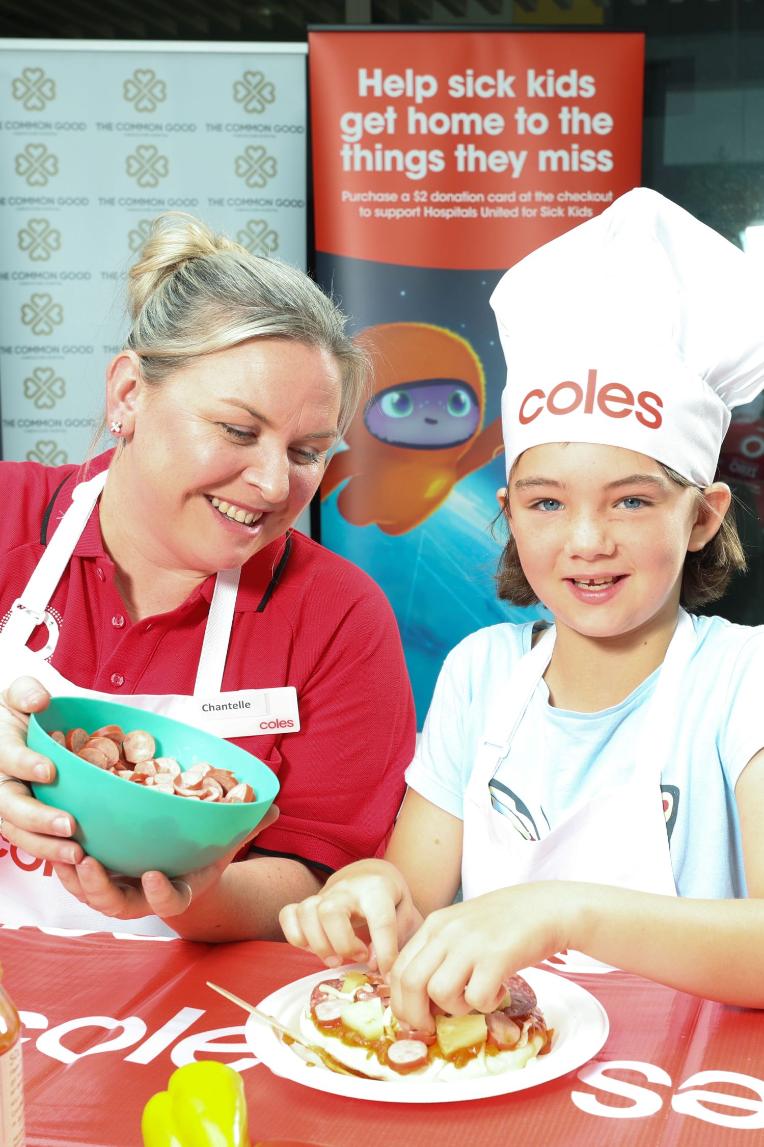 Coles team member Chantelle giving Lucy, 9, a hand making pizza with Mum's Sause.